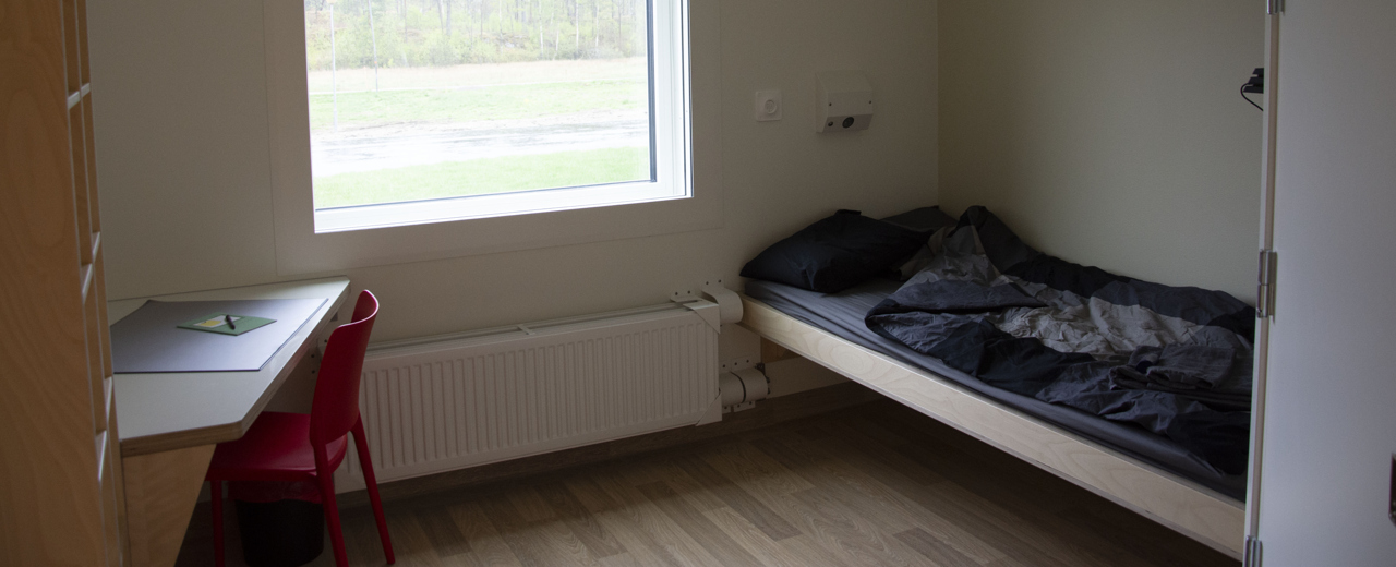 Bild på ett rum med en säng, skrivbord och en stol.